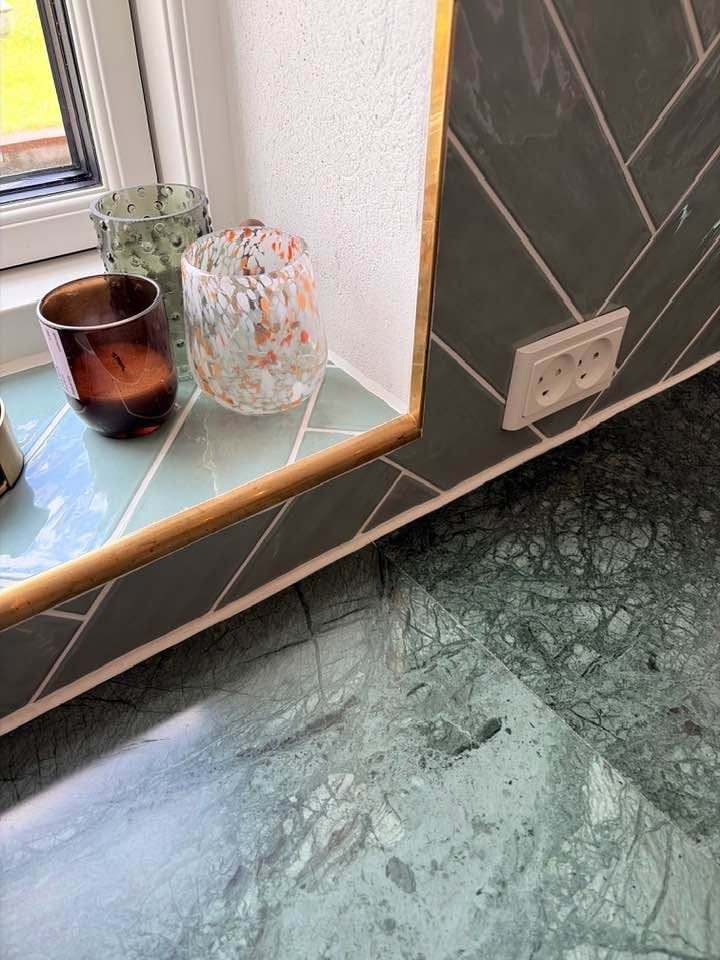 Detalje af vindueskarm med grønne fliser og messingliste